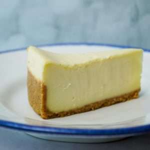 A slice of creamy cheesecake on a white plate.